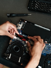 A person working on a laptop with a screwdriver