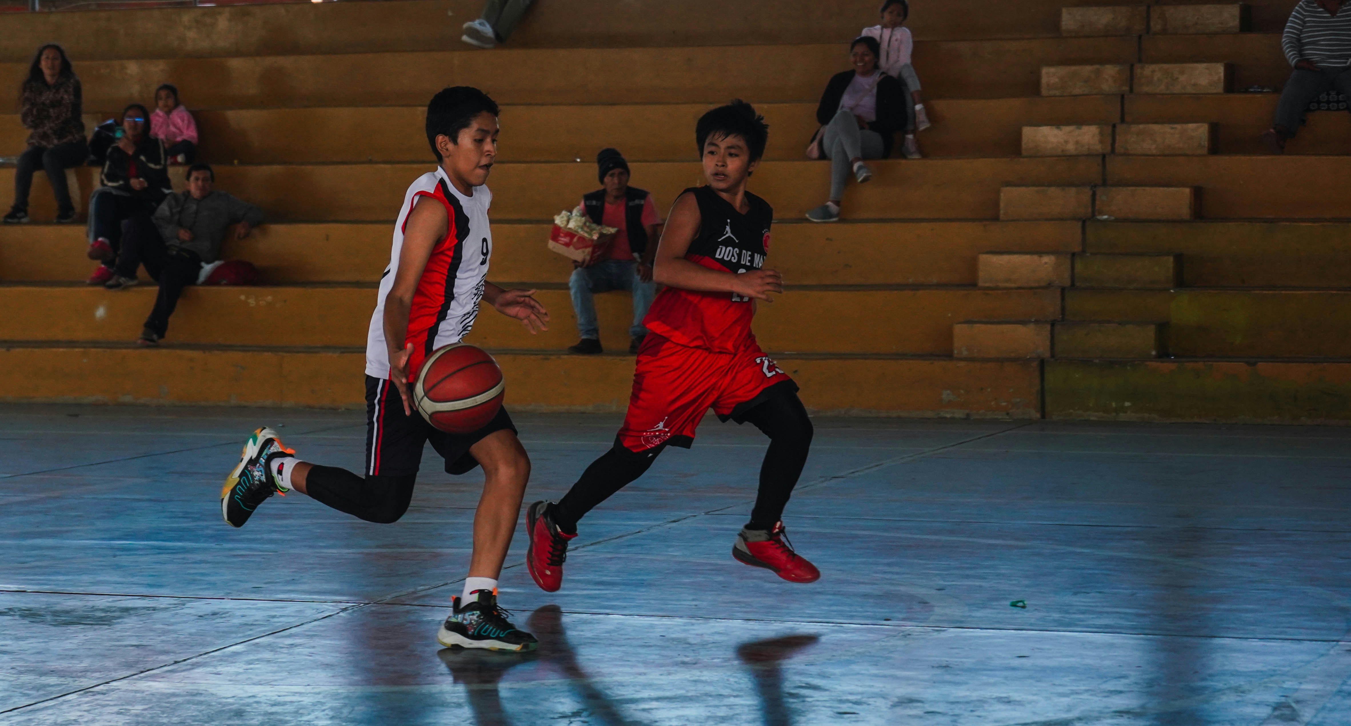 A couple of young men playing a game of basketball