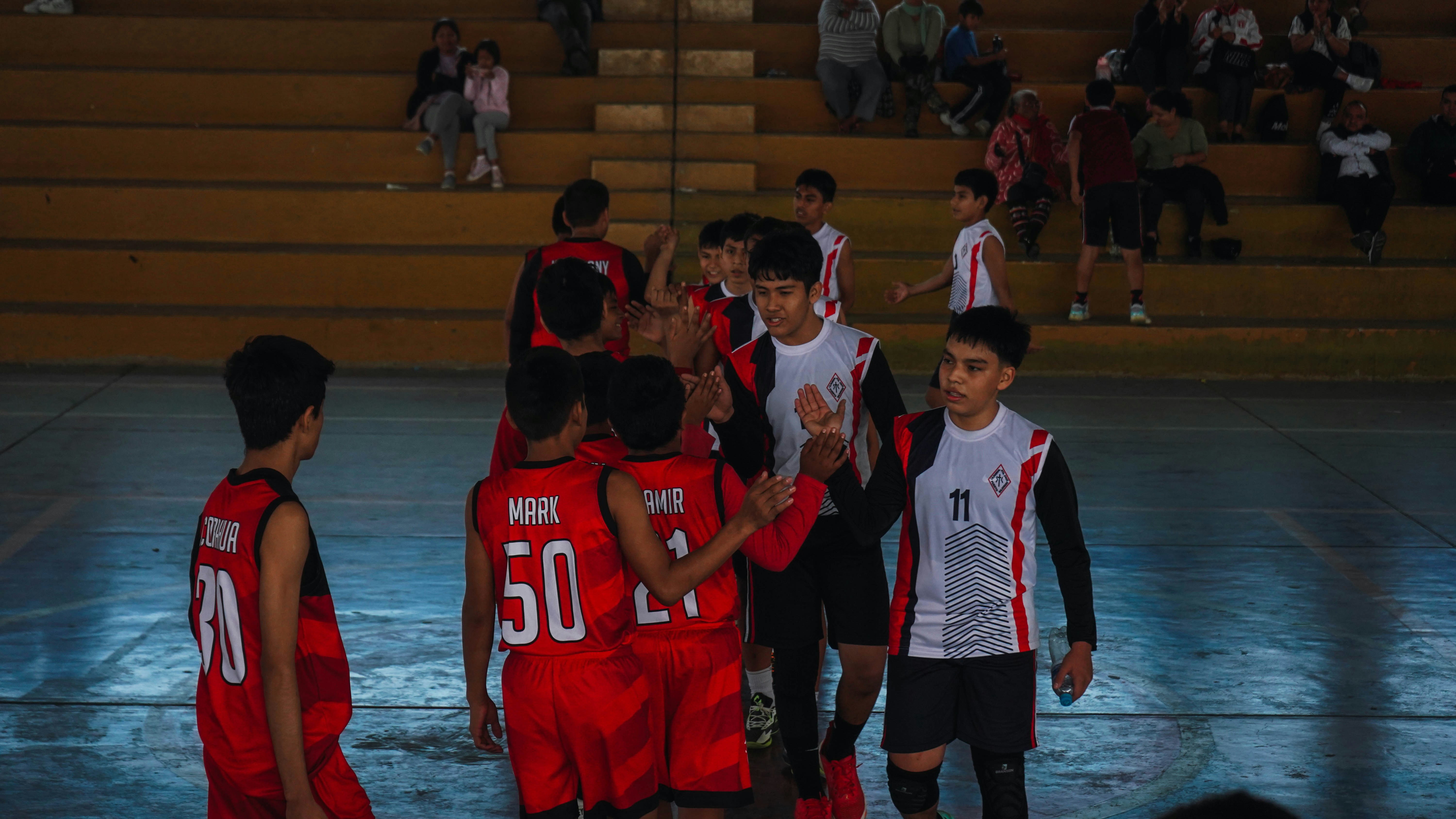 A group of young men standing next to each other on a basketball court