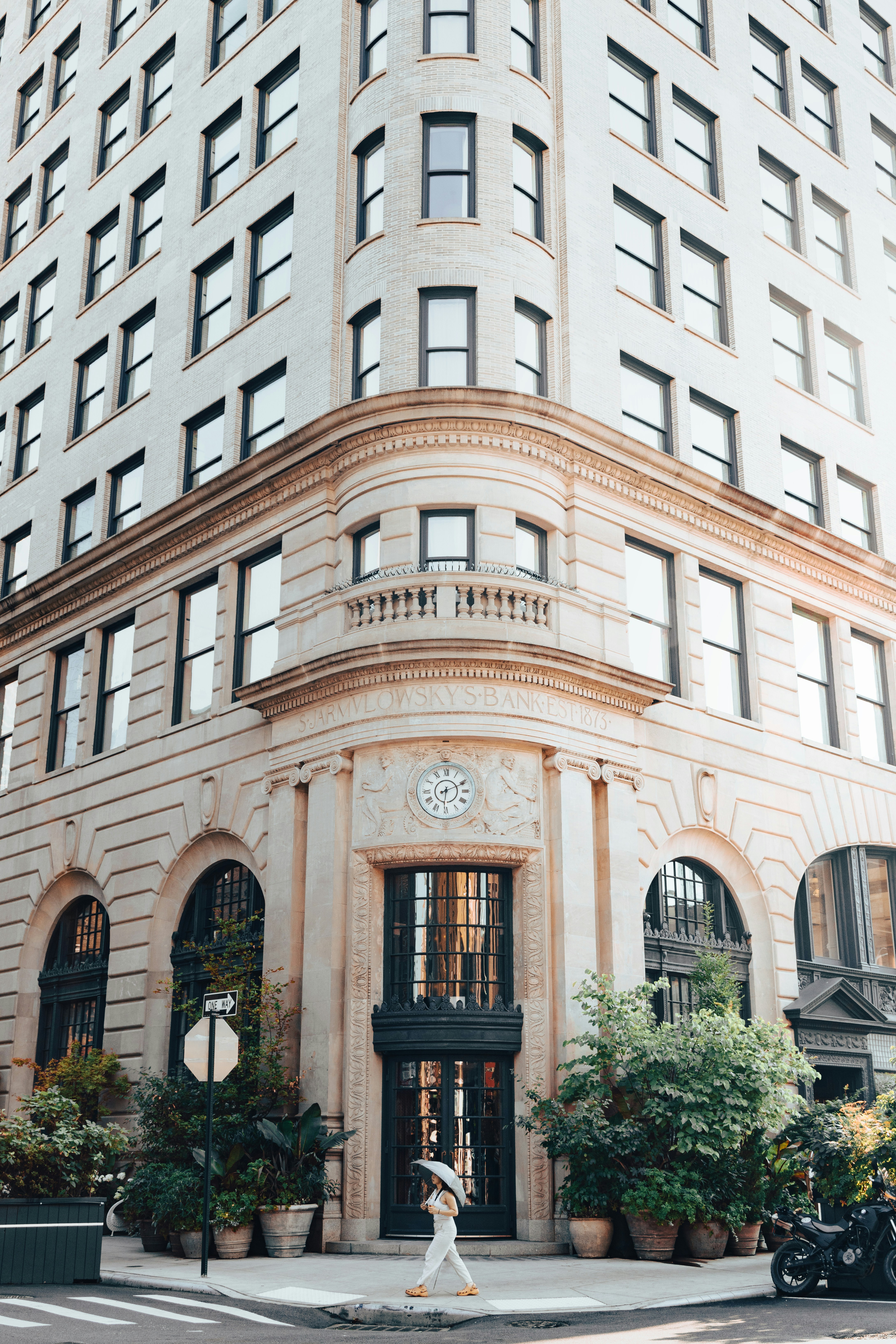 A woman walking across a street in front of a tall building photo ...