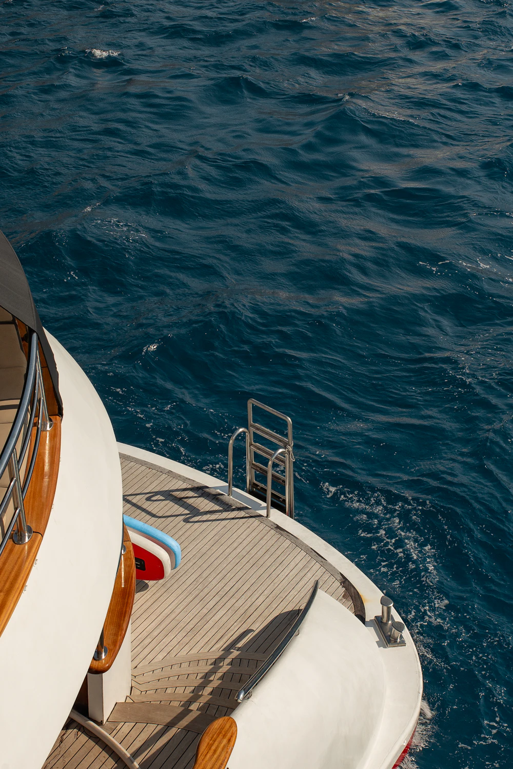Teak aft deck and boarding ladder of a motor yacht over deep blue water