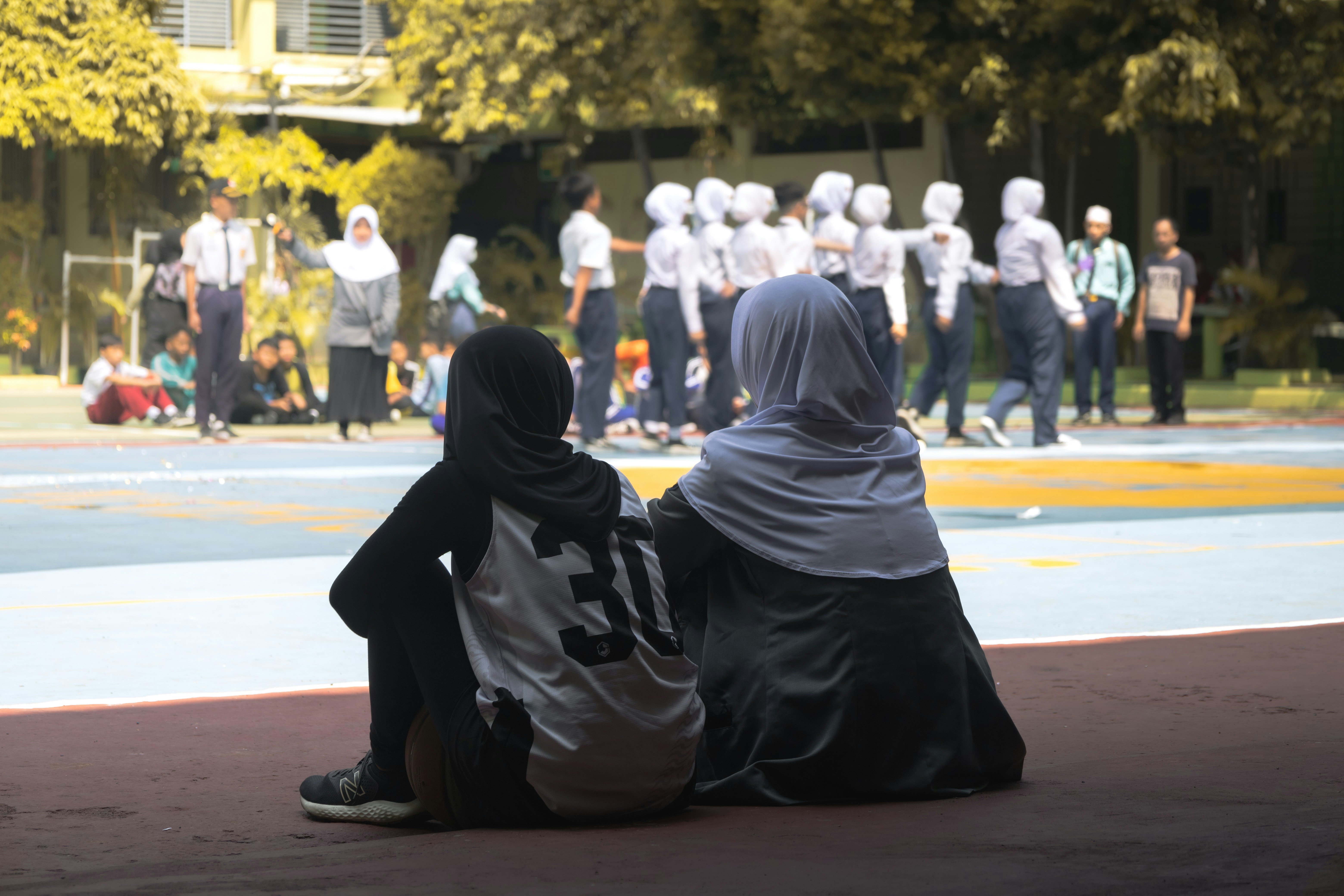 A couple of people sitting on top of a basketball court
