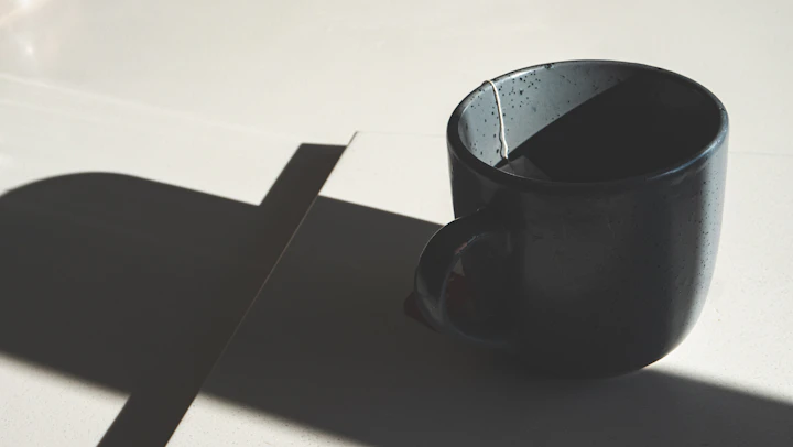 Matte black stoneware mug in raking light — Tenmoku-style iron glaze