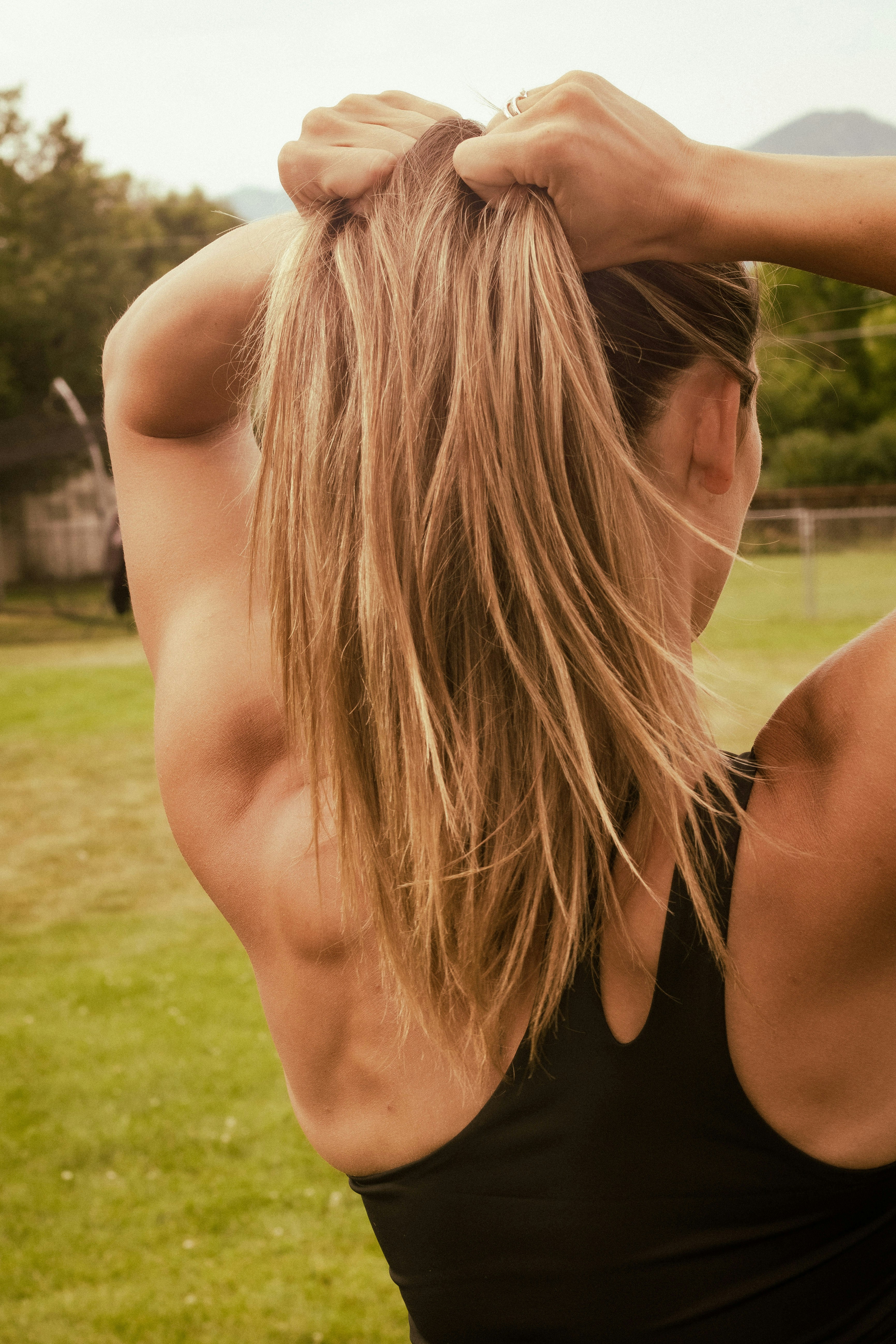 Woman gathering her long blonde hair into a ponytail