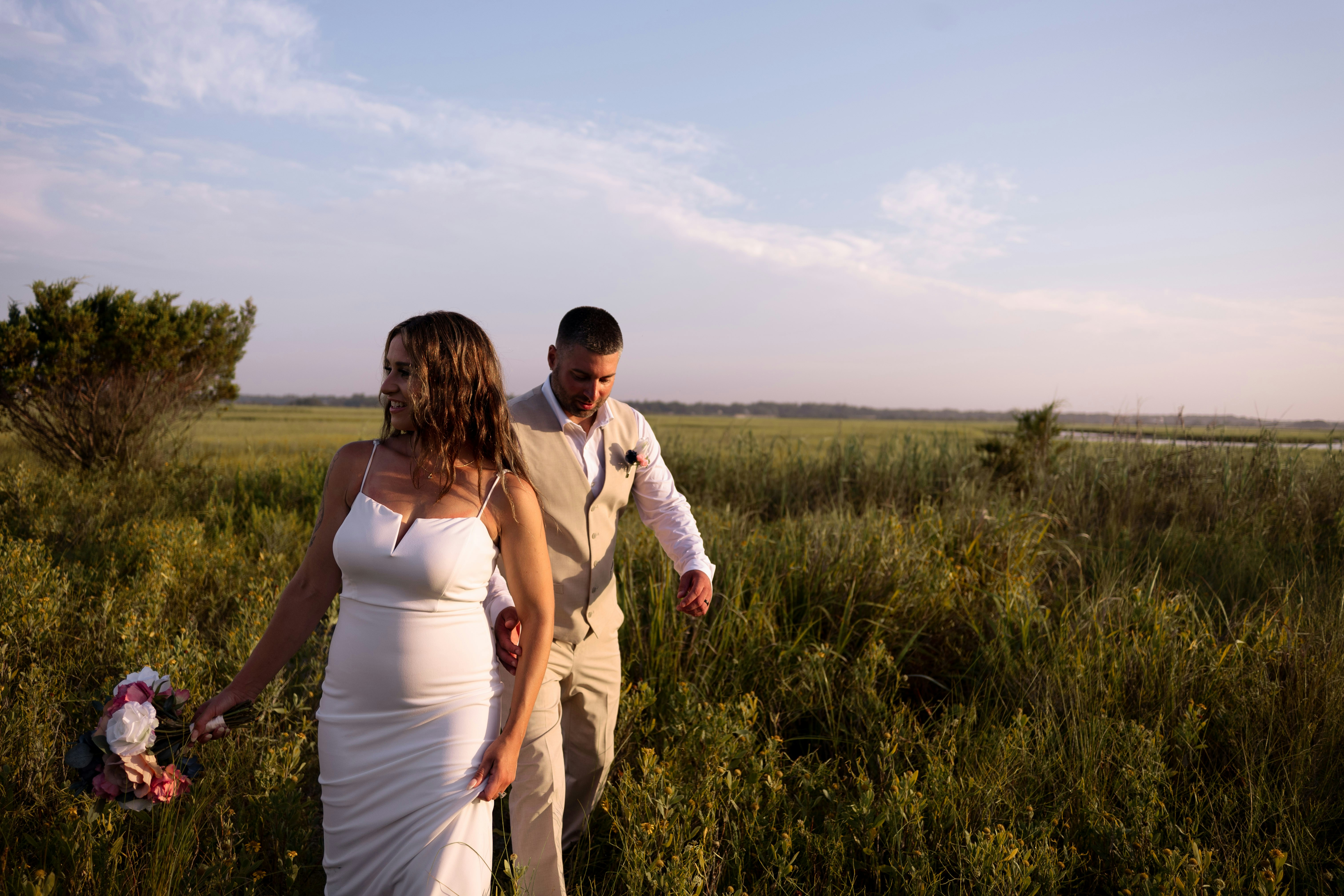 Una novia y un novio caminando por un campo