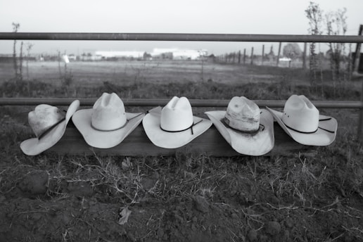 A row of cowboy hats sitting on top of a fence