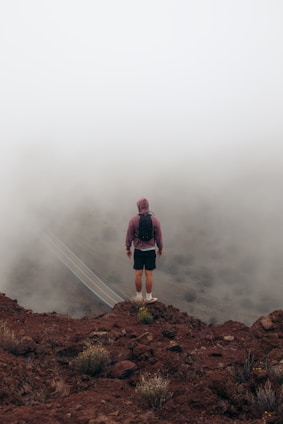 A man standing on top of a mountain in the fog