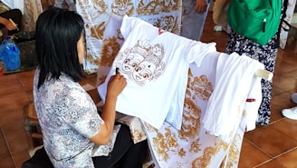 A woman sitting on a chair working on a shirt