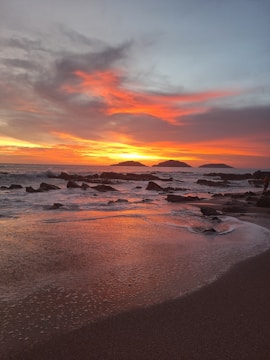 A sunset on a beach with rocks in the water