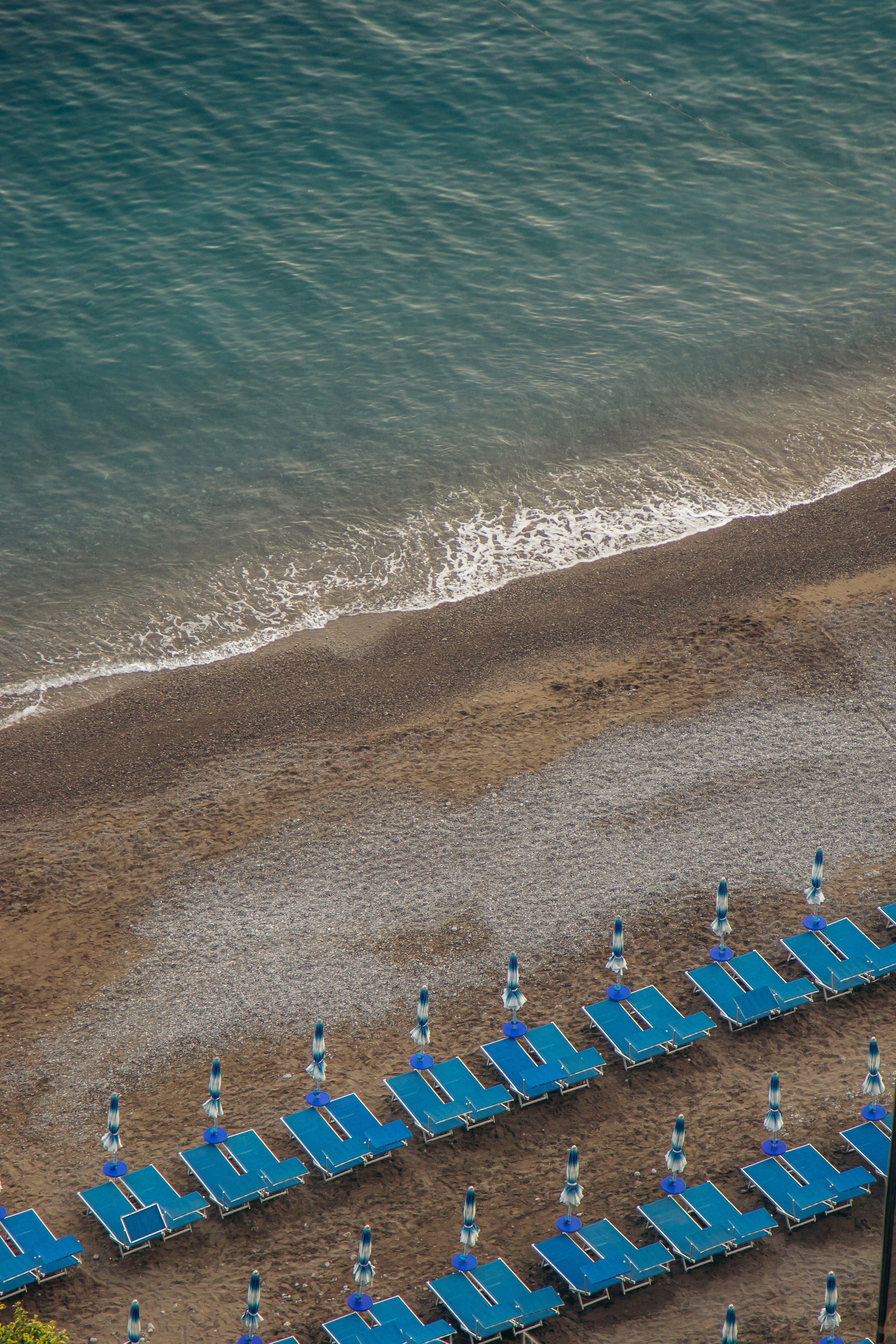 Eine Luftaufnahme eines Strandes mit blauen Stühlen und Sonnenschirmen