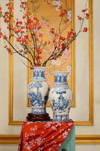 Two blue and white vases with red flowers in them