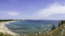 A view of a beach from a hill overlooking the ocean