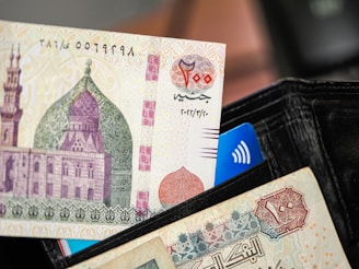 A person holding a wallet with a bank note sticking out of it