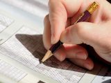 A person holding a pencil and writing on a piece of paper