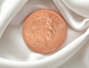 A penny is laying on a white cloth