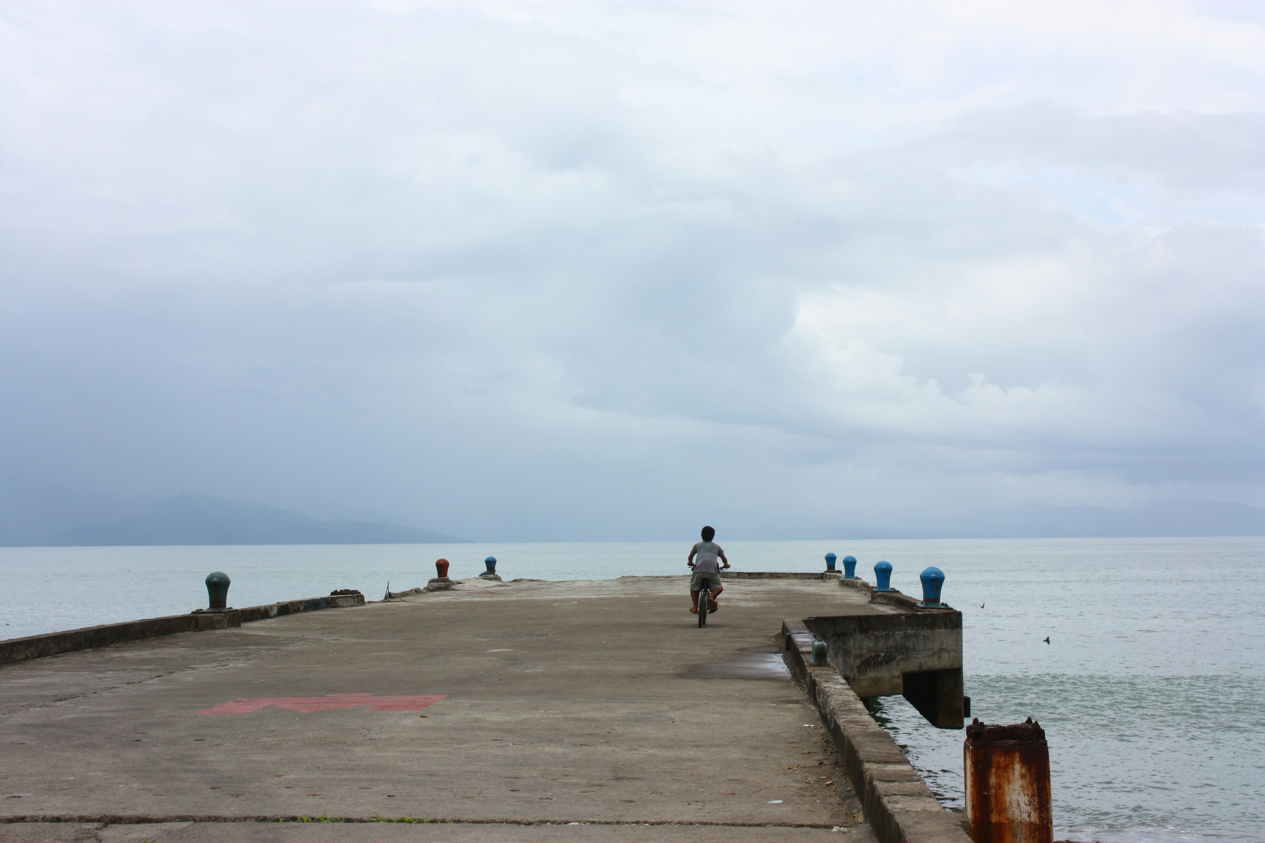 A man riding a bike down a pier next to the ocean