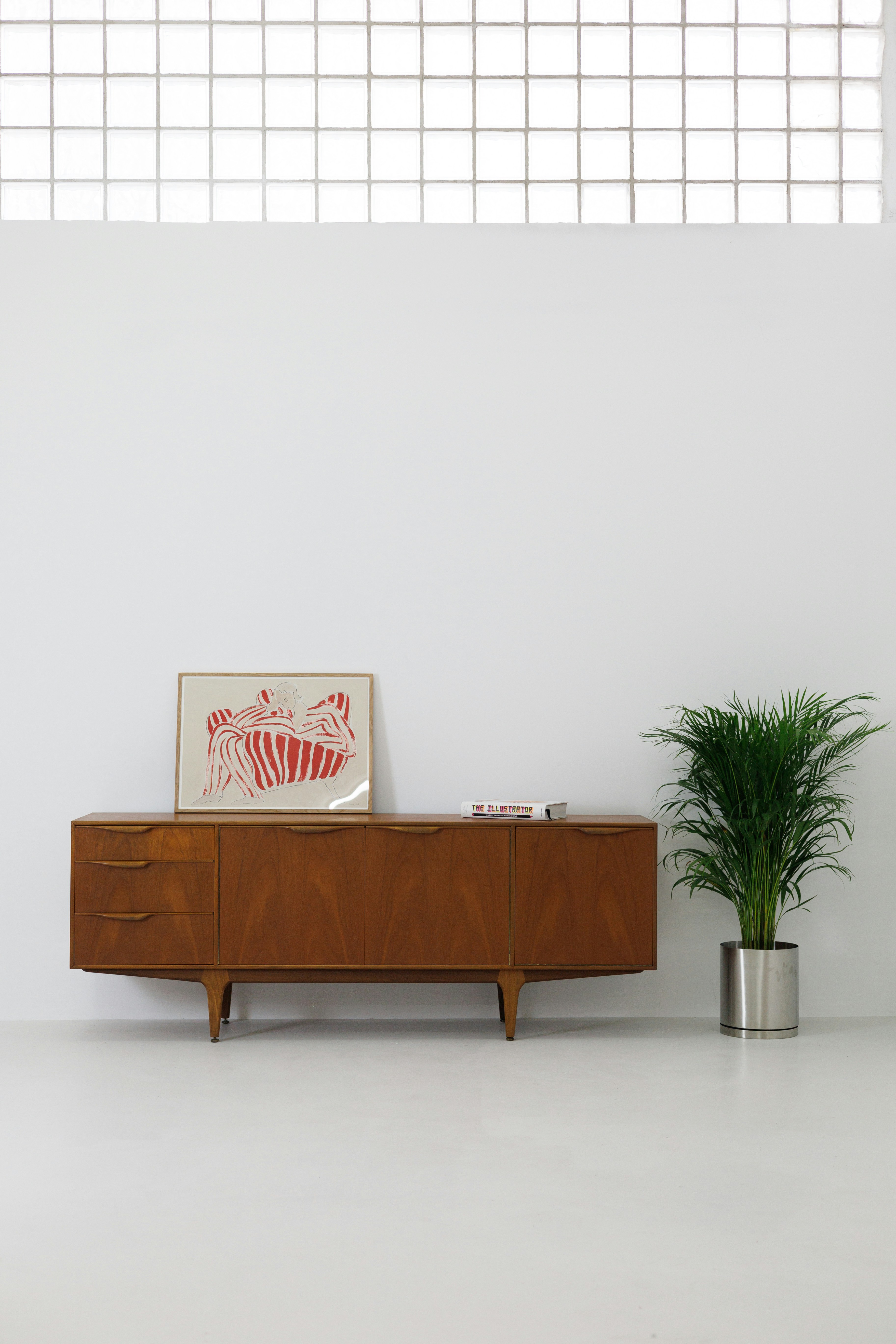 A white room with a wooden cabinet and a potted plant