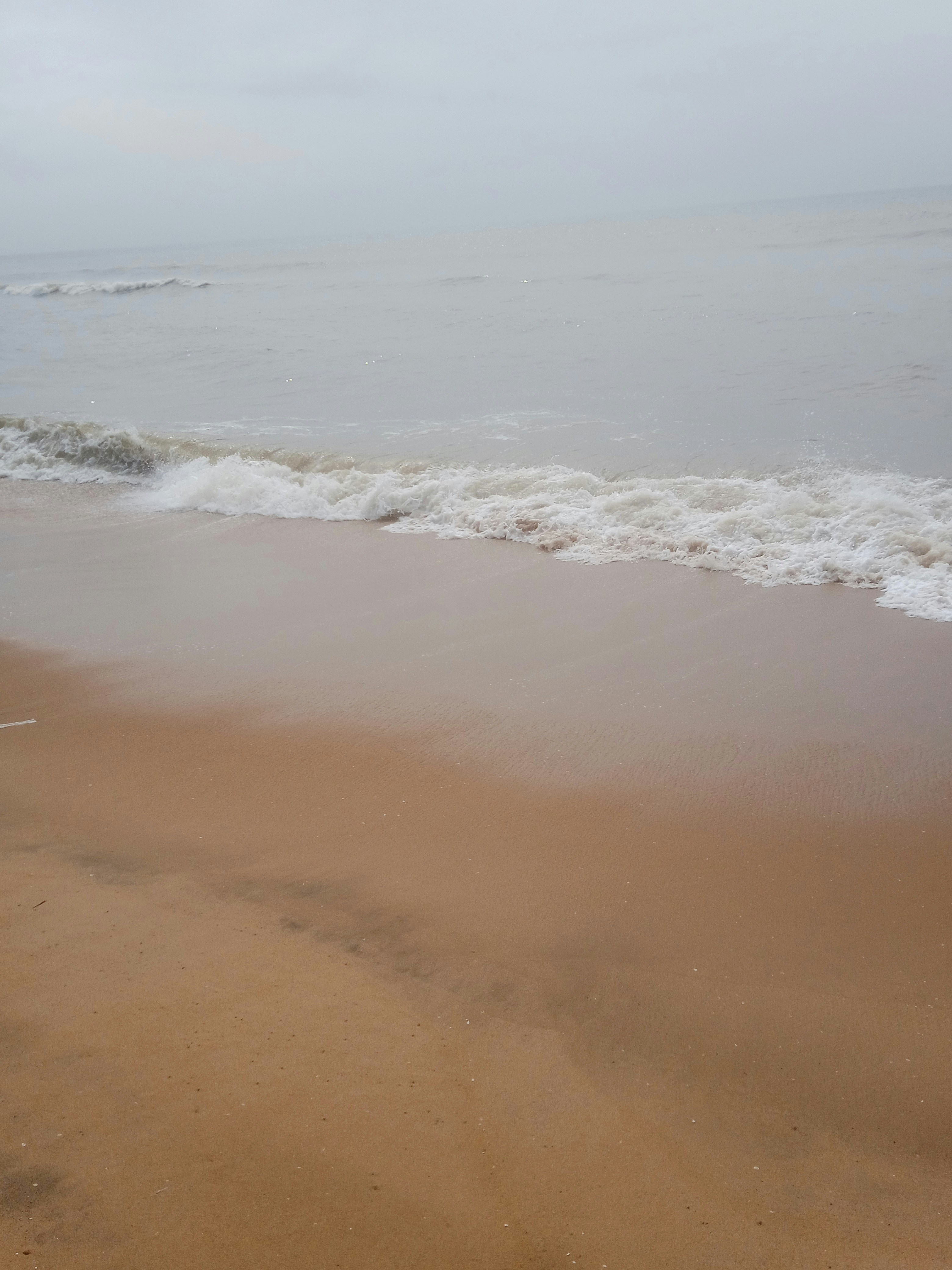 A sandy beach with waves coming in to shore