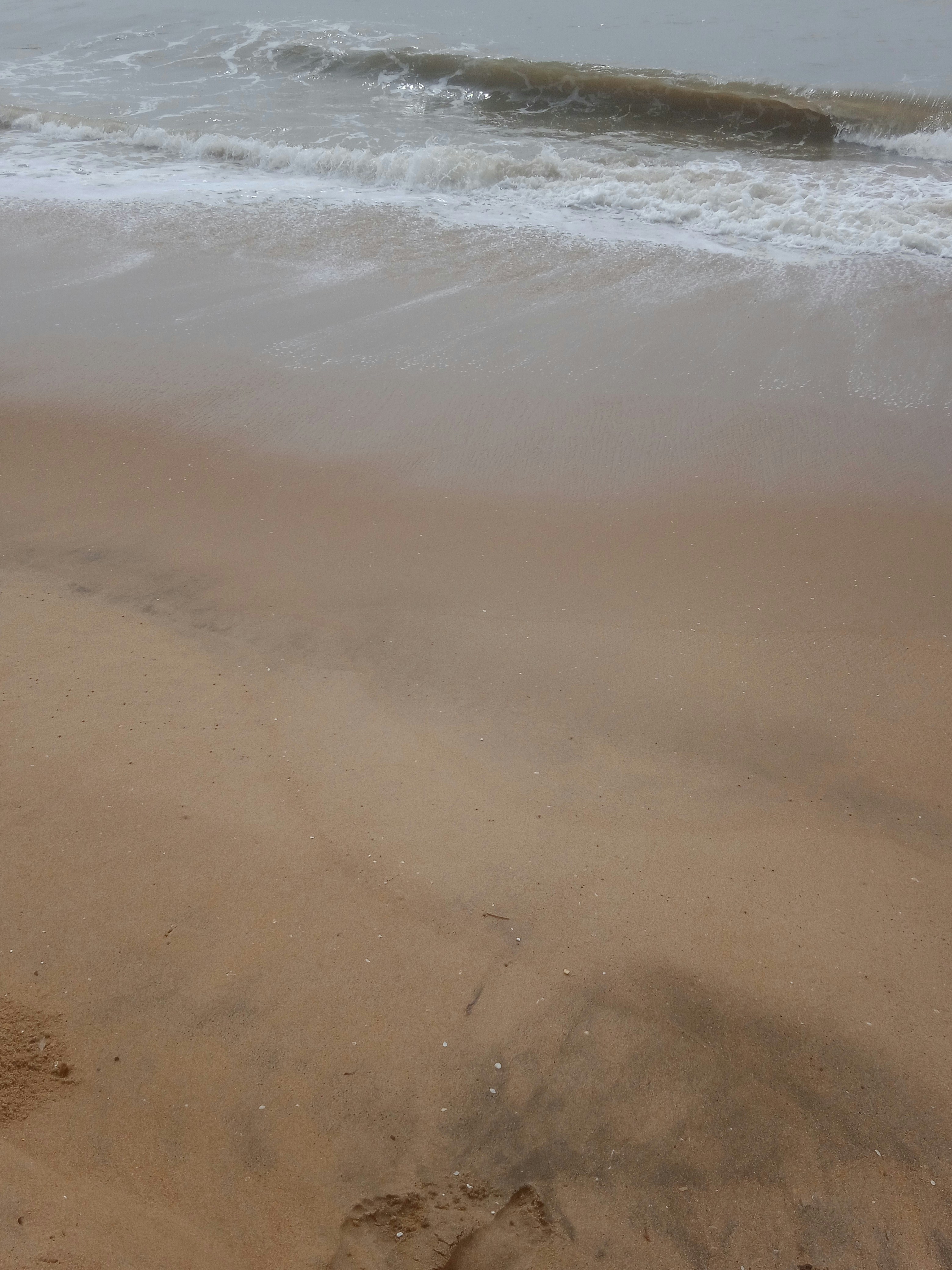 A person walking on a beach with a surfboard