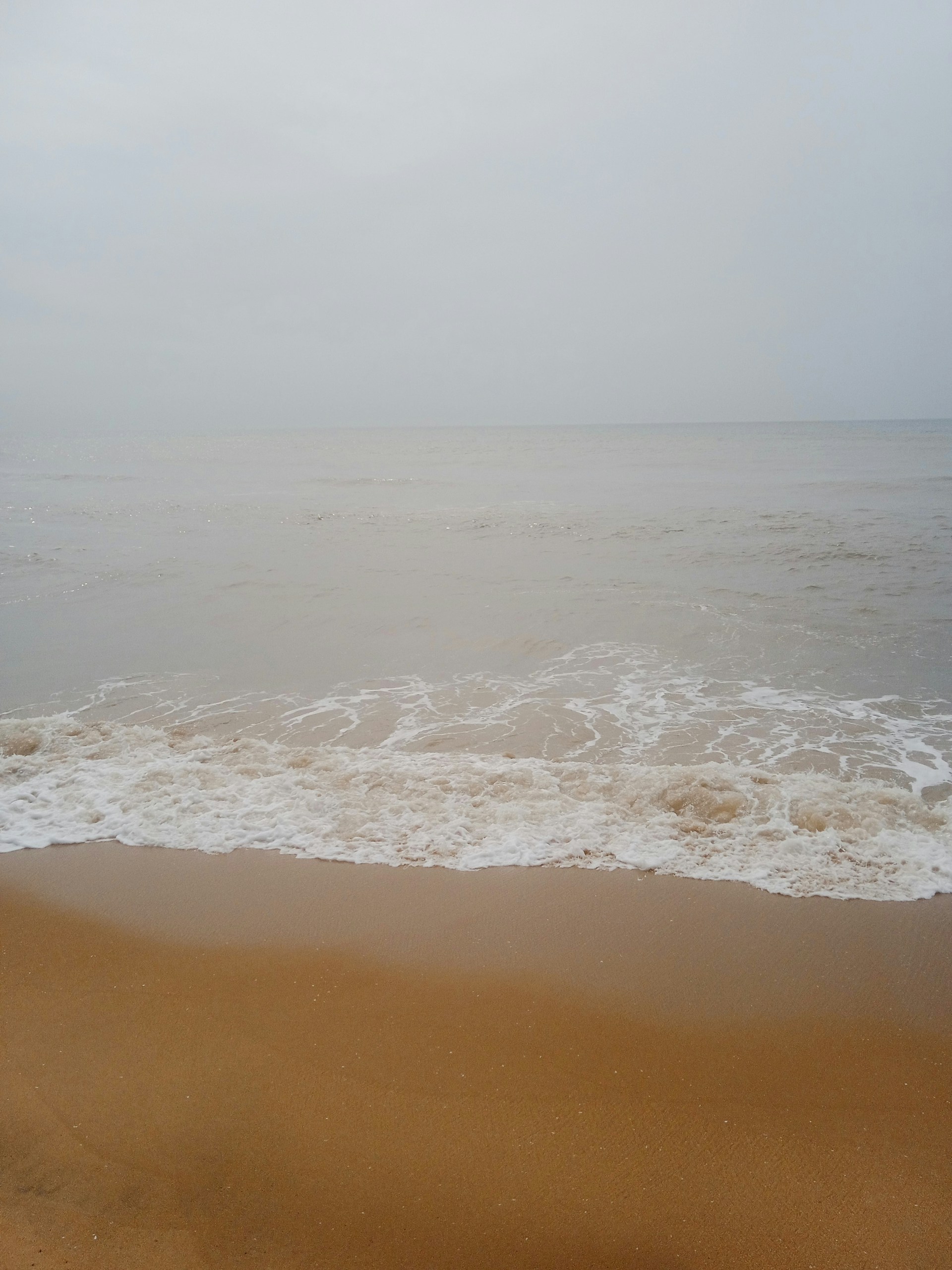 A sandy beach with waves coming in to shore