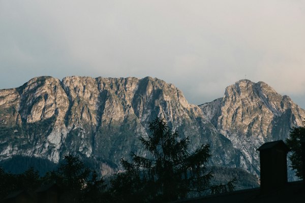 A view of a mountain range with a clock tower in the foreground — Zakopane, Poland