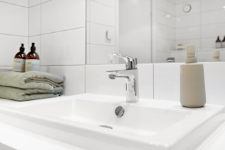 Bathroom sink with folded towels and glass containers creating a fresh relaxing evening setting