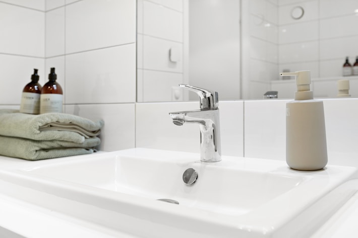 Bathroom sink with folded towels and glass containers creating a fresh relaxing evening setting