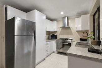 A kitchen with a silver refrigerator freezer next to a stove top oven