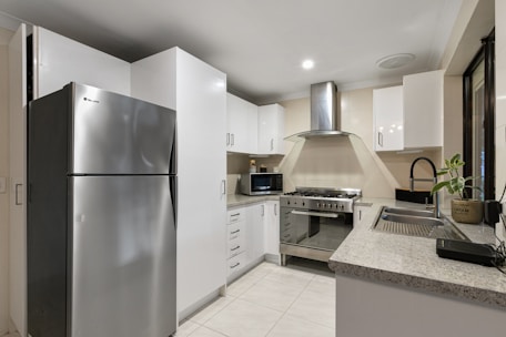A kitchen with a silver refrigerator freezer next to a stove top oven
