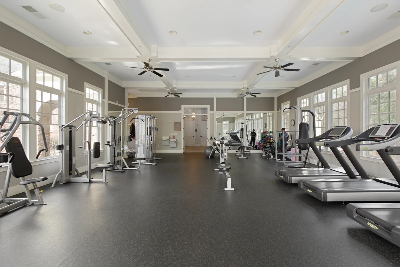 A sunlit gym with an open central floor and equipment along both sides