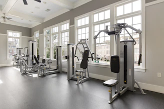 A gym with a lot of machines and windows