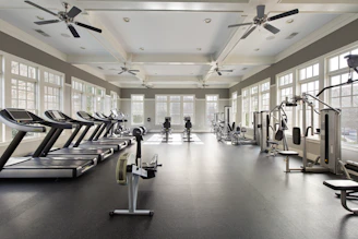 A large gym with a ceiling fan and windows