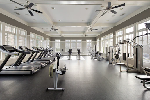 A large gym with a ceiling fan and windows