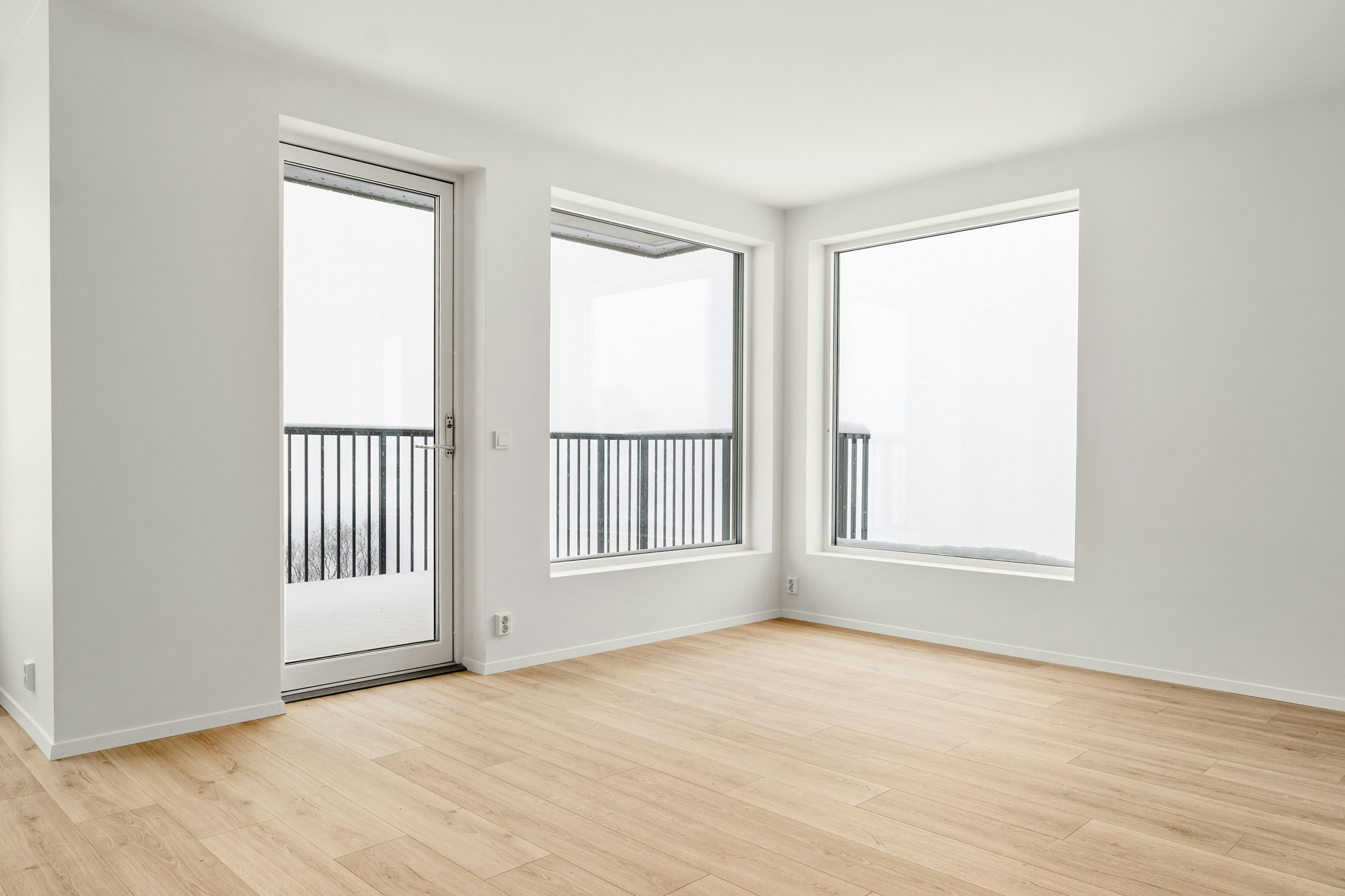 An empty room with three windows and a balcony