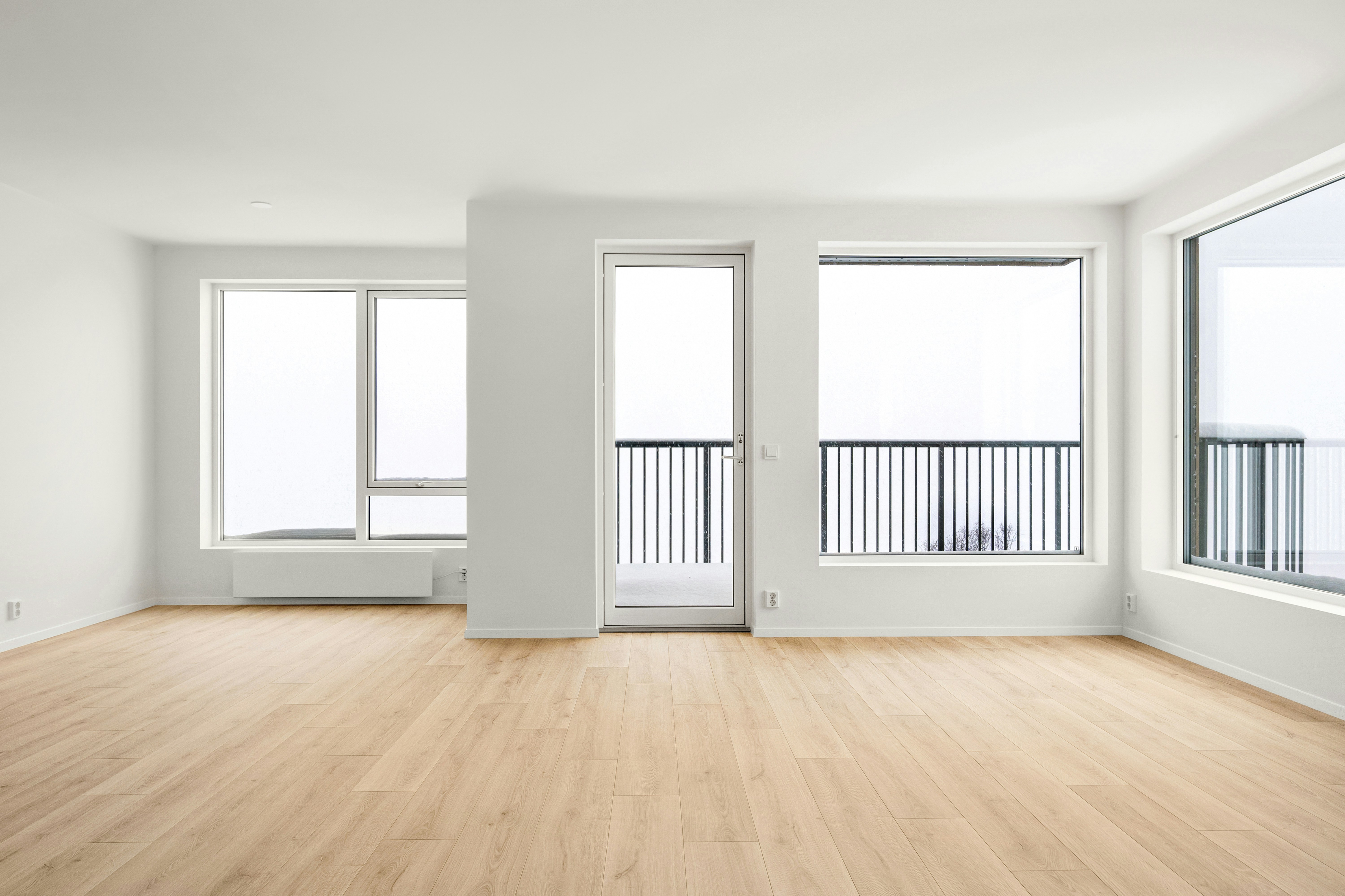 An empty room with wooden floors and large windows