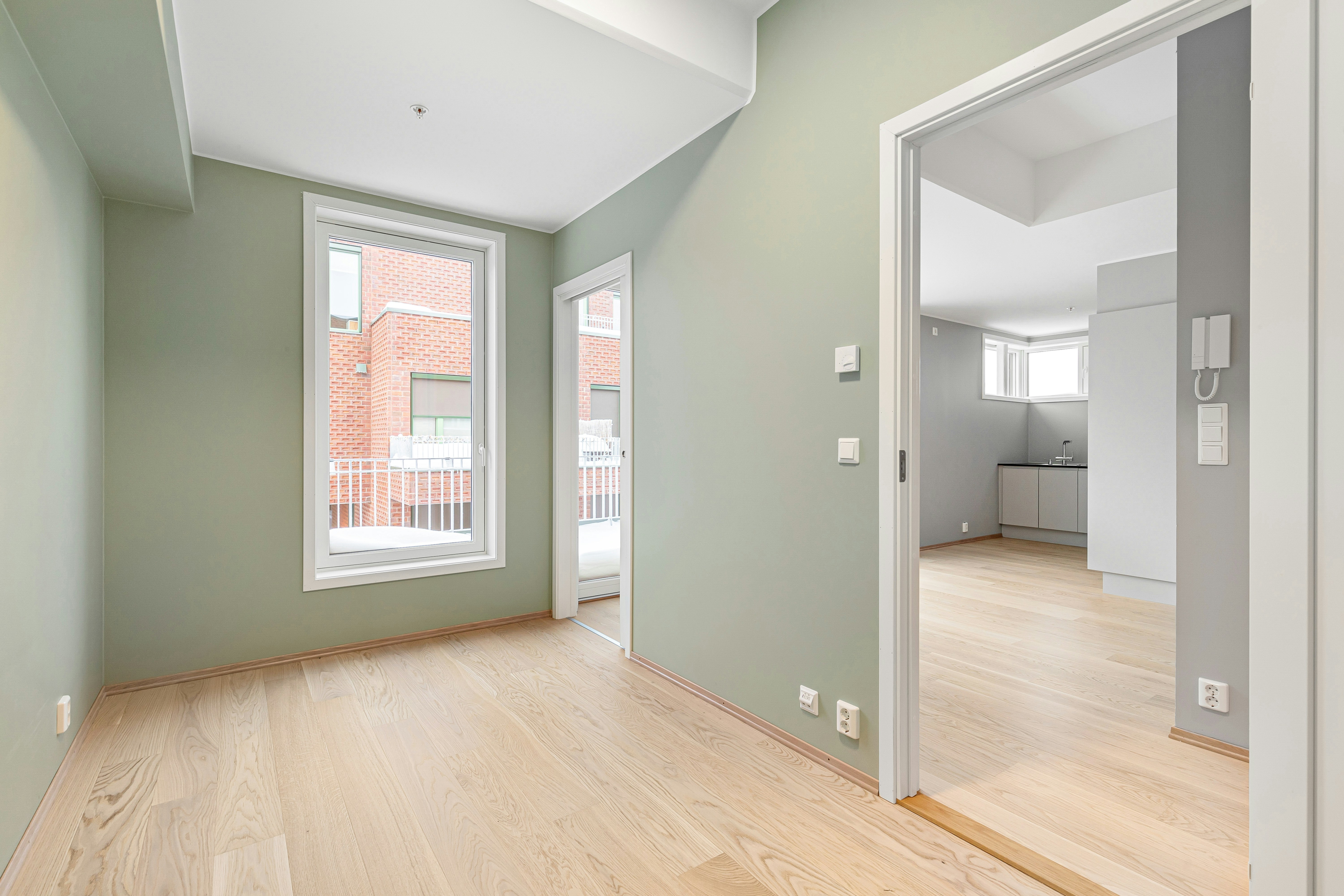 An empty room with green walls and wood floors