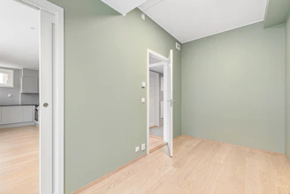 An empty room with green walls and wood floors