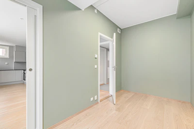 An empty room with green walls and wood floors