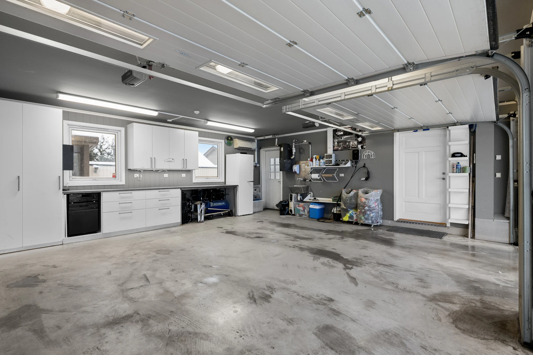 After: the same garage, empty and swept, with clean cabinets along the wall