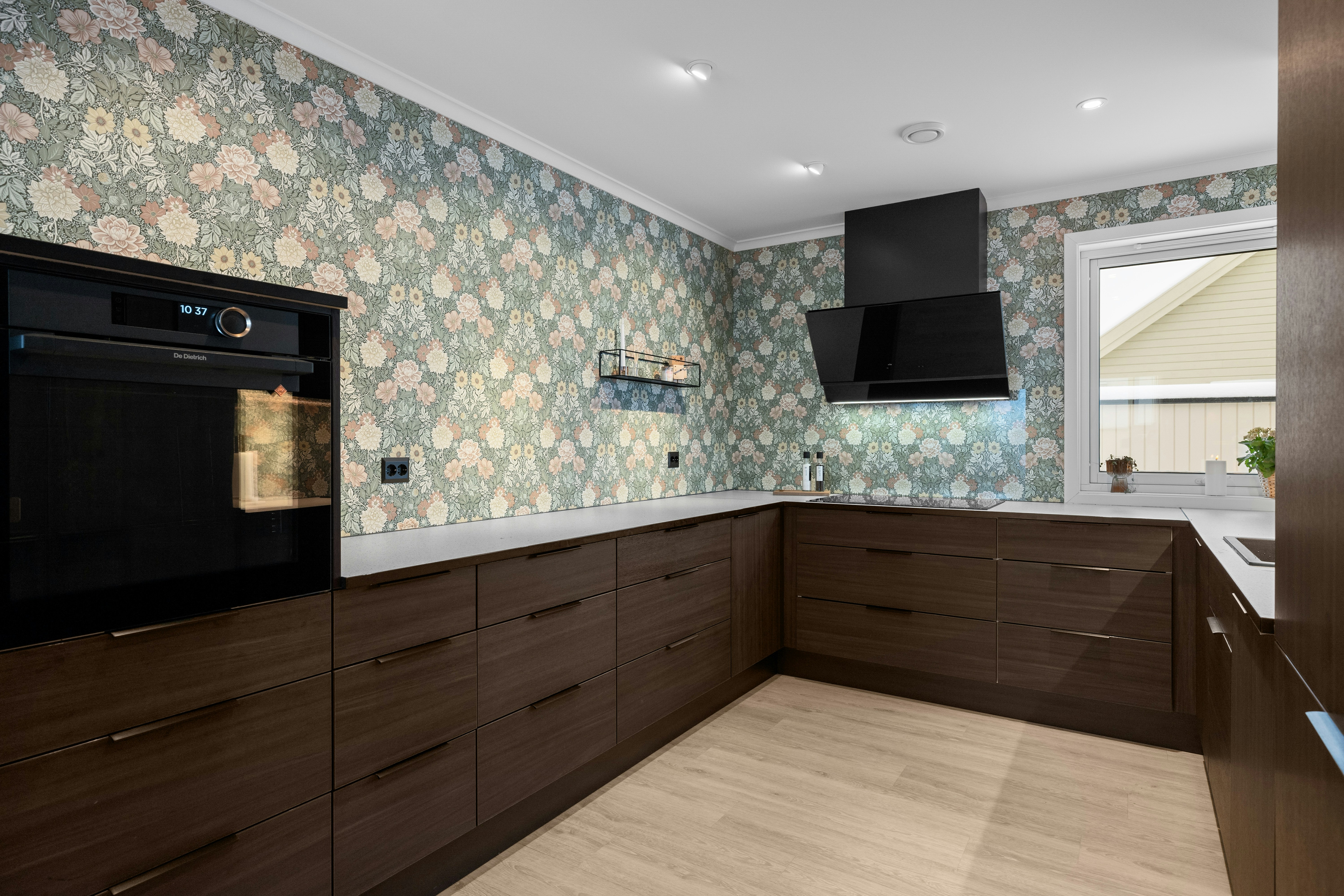 A kitchen with a stove, oven, cabinets and a window