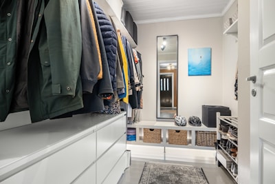 A walk in closet with clothes hanging on a rail