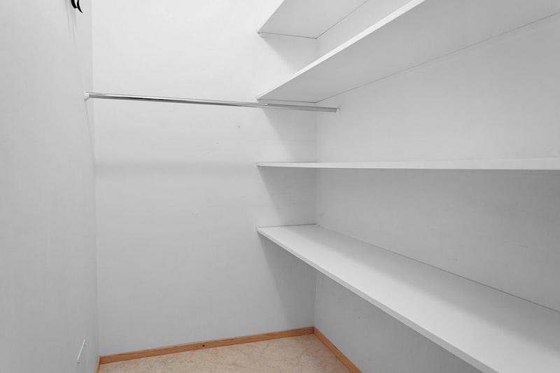 Ankleidezimmer mit hellen Regalen und Holzfußboden
