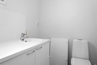 A white bathroom with a sink, toilet and mirror