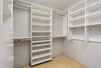 An empty walk in closet with white shelves