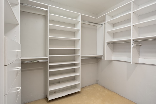 An empty walk in closet with white shelves