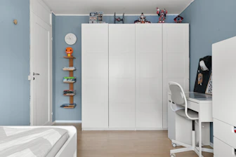 A bedroom with blue walls and white furniture