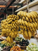 A bunch of bananas hanging from the ceiling of a market