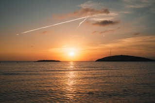 A plane flying over a body of water at sunset