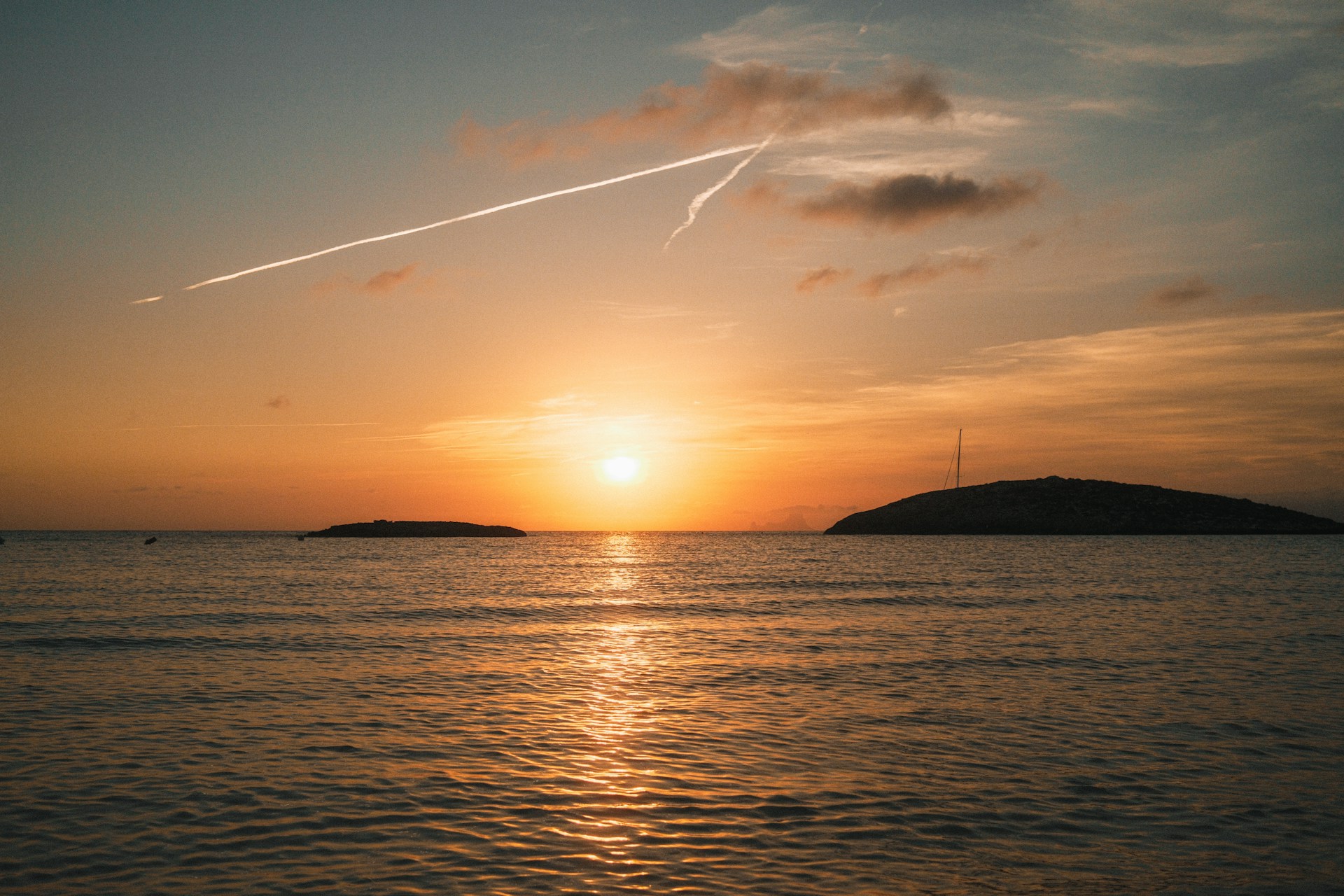 A plane flying over a body of water at sunset