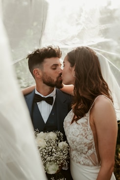 A bride and groom kissing under a veil